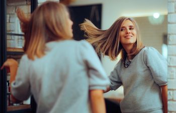 Beauty Salon Customer Admiring her Hair Style in the Mirror. Happy woman loving her new colored coiffure